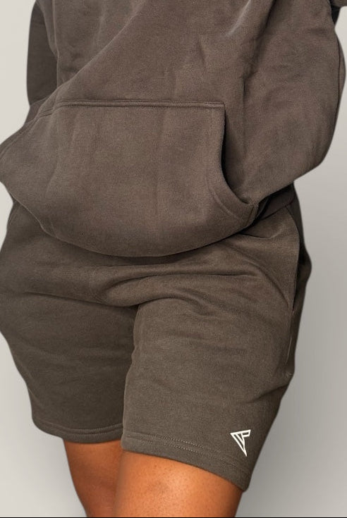 Person wearing a dark gray hoodie and shorts set with 'Curvy Athletics' branding on a light gray background