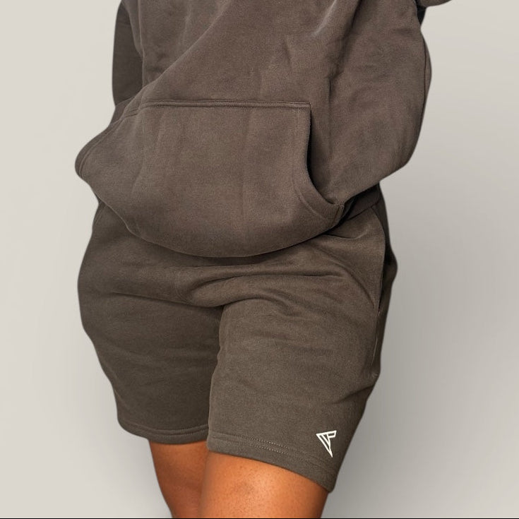 Person wearing a dark gray hoodie and shorts set with 'Curvy Athletics' branding on a light gray background